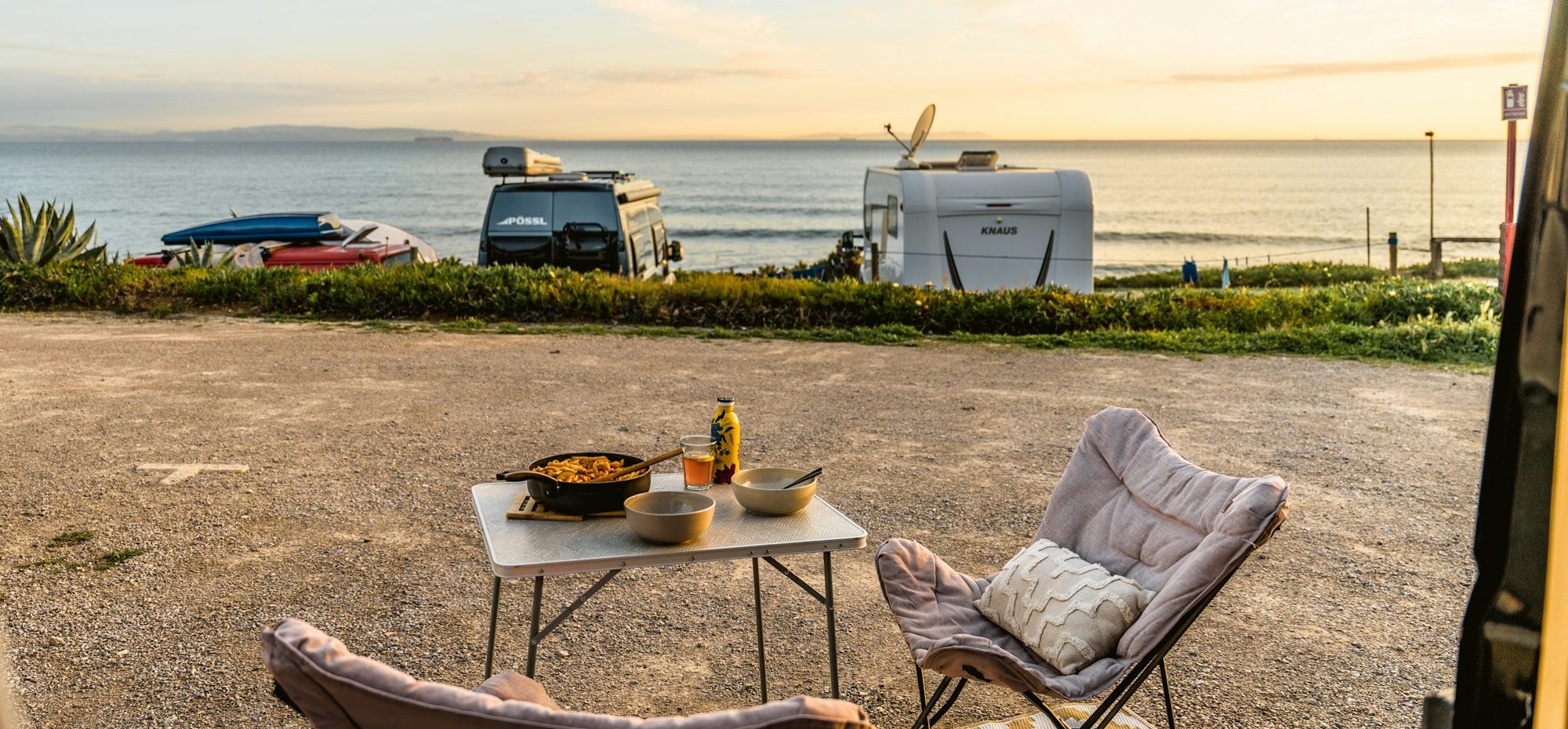 Twee campers aan zee, een tafel gedekt voor het avondeten