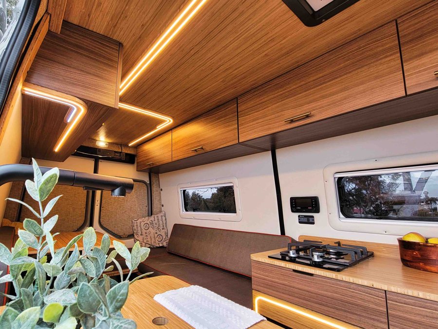 Een warm houten camperinterieur met zithoek en sfeerverlichting