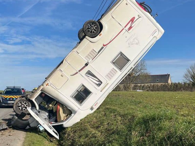 Een camper die in de gracht naast een smalle weg is gekanteld